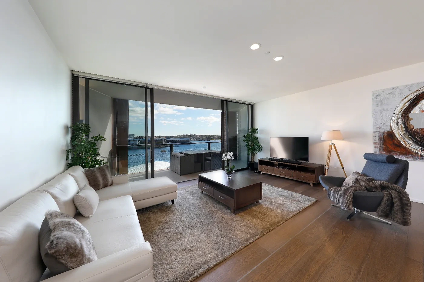 Furnished living room opening to a harbour balcony at a Westprecinct serviced residence in Barangaroo