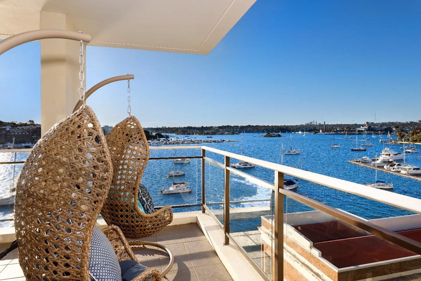 Balcony with hanging egg chairs overlooking the marina and harbour at a Westprecinct serviced residence in Rozelle